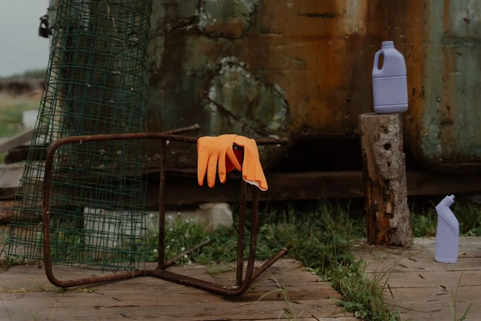 Hands in yellow gloves cleaning wall with sponge and spray bottle.